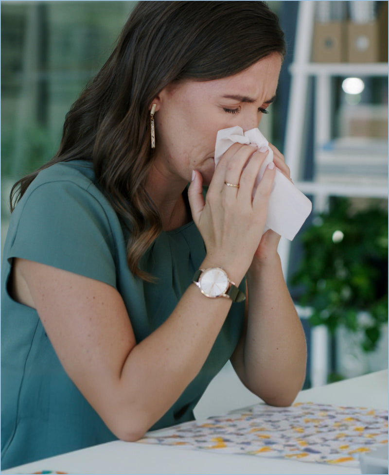 Woman blowing her nose while feeling unwell